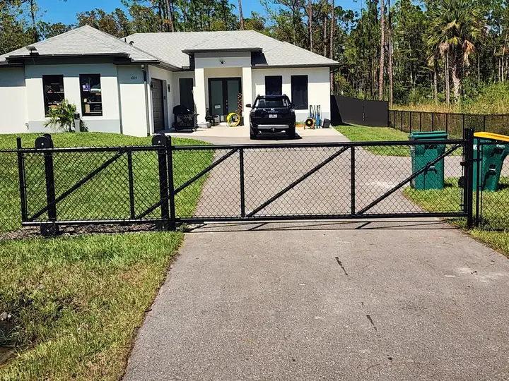 Black chain link double driveway gate at a home in Naples Florida
