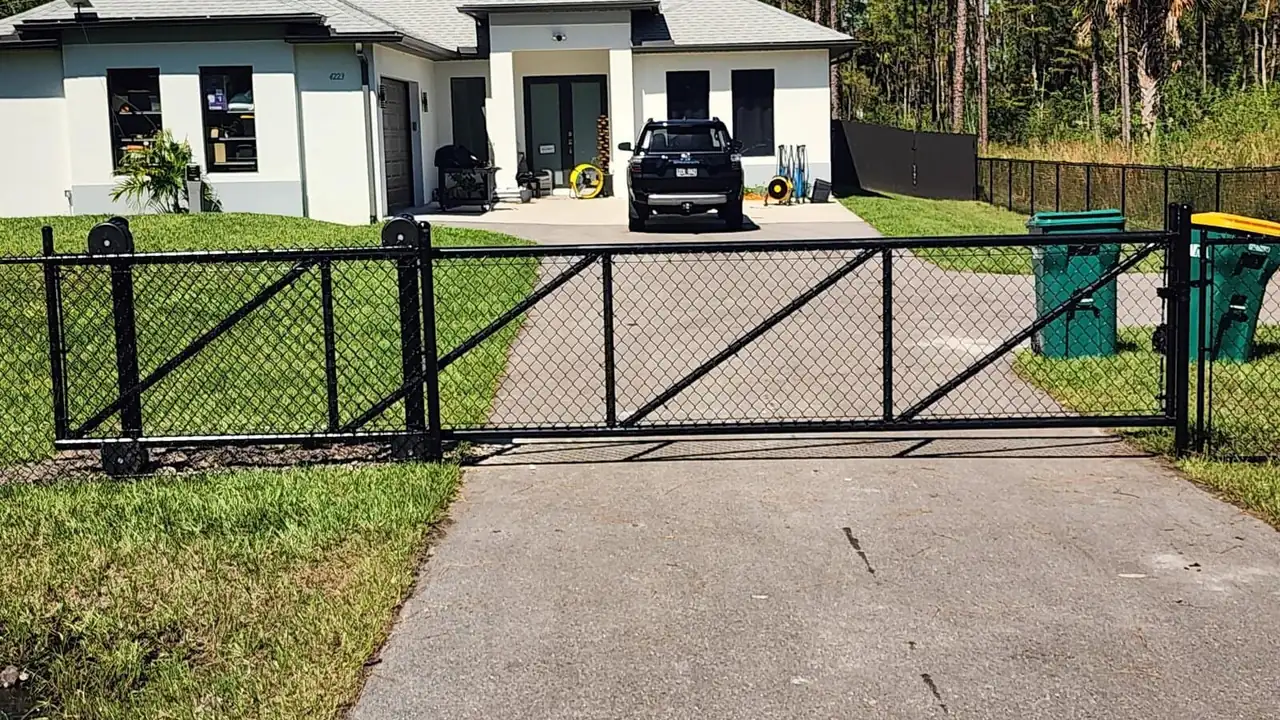 Black chain link driveway gate at a Naples home